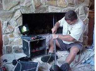 A man is using chimney rods with a monitor and camera to capture images of a chimney. 