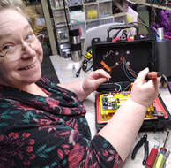 A smiling lady, Alicia, is wiring a Chim-Scan® Controller electrical board.