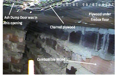 An area under the firebox floor has charred plywood and combustible wood.