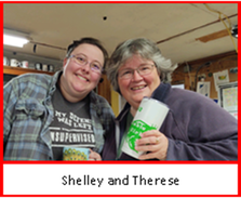 Two ladies are smiling. One is holding a coffee cup.