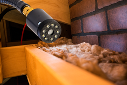 A cylindrical Enviro camera with 9 LED lights is inspecting a fireplace smoke shelf.